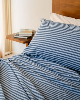 Bed with blue striped bedding and a wooden headboard in a bedroom setting.