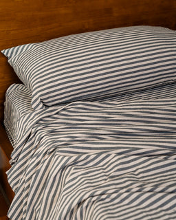 Striped bedding with a pillow on a wooden bed frame
