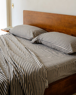Bed with striped bedding and pillows in a bedroom setting.