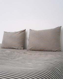 Two striped pillows on a matching striped bedspread against a white background