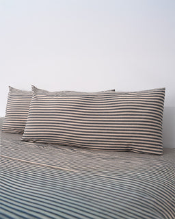 Striped bed sheets and pillowcases on a bed with a plain background