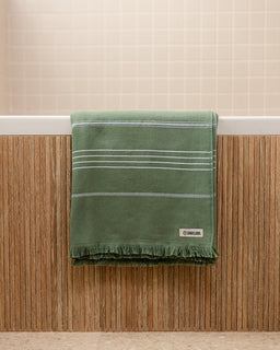 Green towel with white stripes on a wooden surface