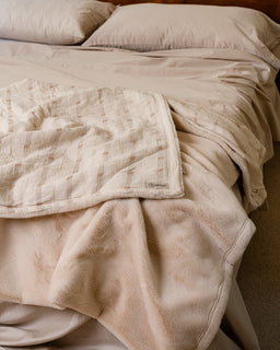 Beige quilted blanket on a bed with pillows