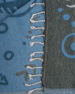 Close-up of a blue and gray fabric with patterns and frayed edges.