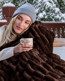 Women in a beanie holding a chocolate cover blanket close to her face