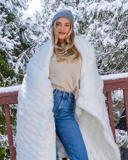Girl on deck with snowy tree background wrapped in snow colored cozt drift blanket