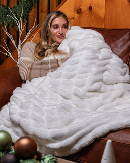 Girl on sofa in cabin with cozy snow colored drift blanket 