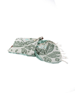 Green leaf-patterned towel with tassels on a white background