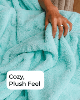A close-up of a soft, plush turquoise blanket with a hand resting on it. A white label in the lower-left corner reads 'Cozy, Plush Feel'.