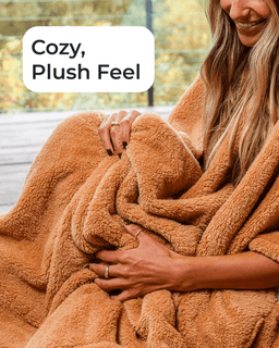 A woman wrapped in a cozy, plush tan fleece blanket, with a white text overlay that reads 'Cozy, Plush Feel'.