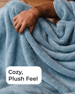 A close-up of a person holding a soft, plush blue blanket. A white rounded text box in the lower left reads 'Cozy, Plush Feel'.
