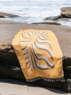 Yellow towel with leaf pattern on a rock by the ocean