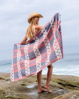 Woman holding a patterned towel by the ocean