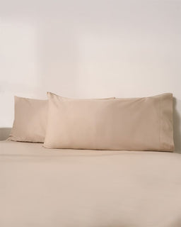 Beige pillowcases on a beige bed against a plain wall