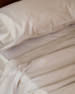 Beige bedding set with pillows on a bed