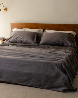 Bed with gray bedding and pillows in a bedroom setting.