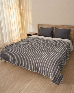 Bed with striped duvet and pillows in a bedroom setting