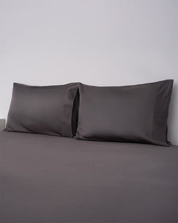 Gray bedding set with two pillows on a plain background