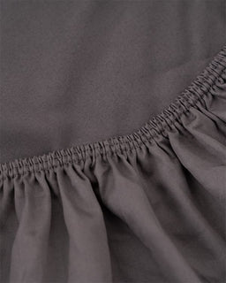 Close-up of a gray fitted sheet with a elasticized waistband.