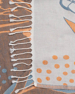 Close-up of a textured fabric with tassels and a patterned surface.