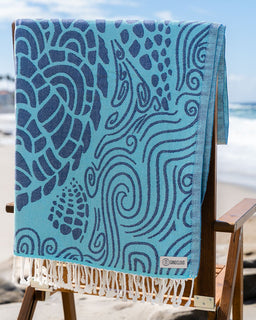 Blue towel with turtle pattern on a wooden chair at the beach
