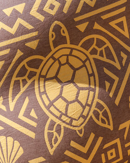 A close-up of a brown textured surface featuring a gold turtle illustration and geometric tribal-style patterns.