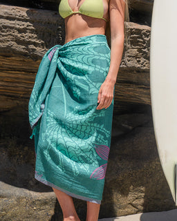 Women at rocky beach wearing teal floral beach towel as a sarong