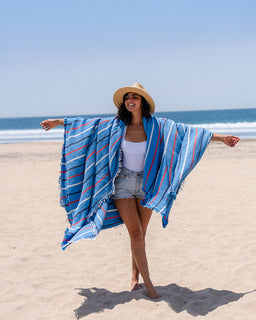woman on the beach with pinstripe blue and red party blanket