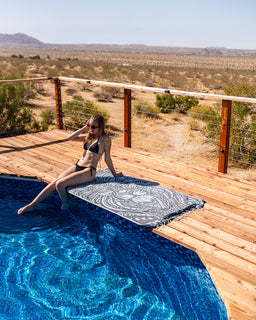 Woman sitting by a pool with a scenic desert view