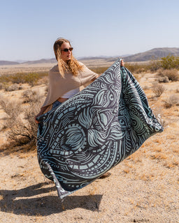 Person holding a black and white patterned blanket in a desert setting
