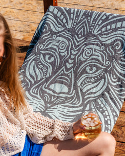Person holding a drink on a patterned blanket outdoors