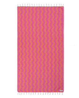 Pink and orange wavy patterned towel with white tassels on a white background