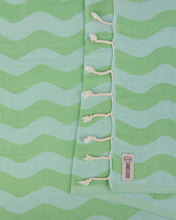 Green and light blue striped fabric with tassels and a brand label.