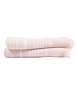 Pink folded bath towels with white stripes on a white background