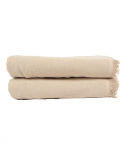 Two folded beige woven bath towels with fringed edges, stacked on a plain white background.