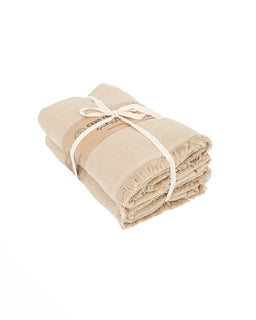 A folded beige cotton bath towel with fringed edges, tied with a cream ribbon and a paper band label, on a solid white background.
