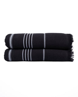 Two folded black towels stacked on a white background, each with thin white vertical stripes and fringed edges.