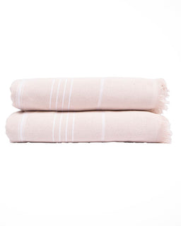 Two folded light pink cotton towels stacked on a white background, featuring thin white vertical stripes and fringed edges.