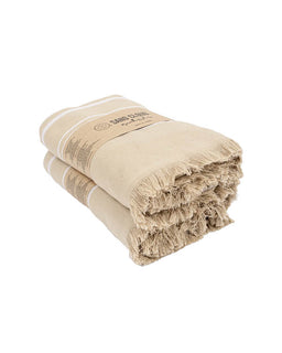 Two folded beige cotton towels with fringed edges and a paper band label, photographed on a clean white background.