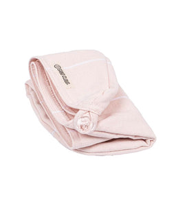 A folded light pink cotton hair towel with thin white stripes and a small embroidered brand label reading on a white background.