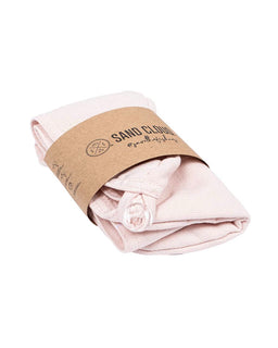 A folded light pink cotton hair towel wrapped in a brown kraft paper band printed with the brand name 'SAND CLOUD' and 'handcrafted', shown on a plain white background.