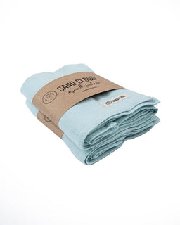 Folded light blue towel with a brown paper label on a white background