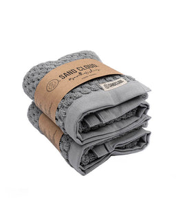 Stack of gray towels wrapped in brown paper with 'Sand Cloud' branding on a white background