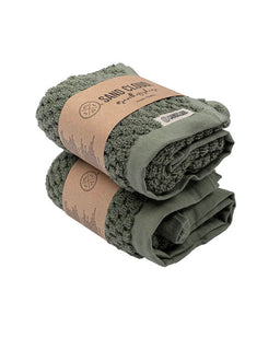 Two folded green towels with brown paper wraps and visible branding on a white background
