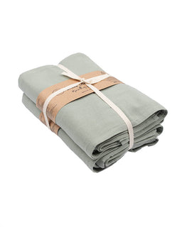 Folded light green fabric with a brown ribbon on a white background