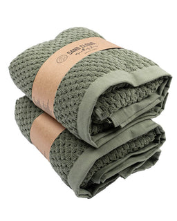 Folded green towel with a brown band and visible brand name on a white background