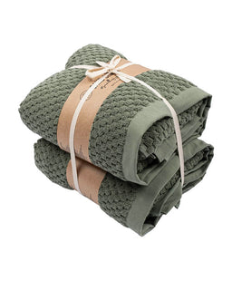 Stack of green towels tied with a brown ribbon on a white background