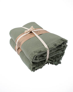 Green towel with fringe edges tied with a beige ribbon on a white background