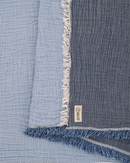 Blue textured fabric with frayed edges and a brand label.