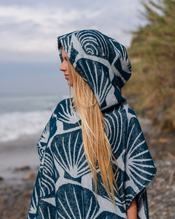 Person wearing a blue and white patterned hooded poncho on a beach